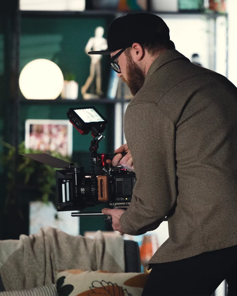 Caméra cinéma manipulée par un chef opérateur sur un tournage en décor intérieur.