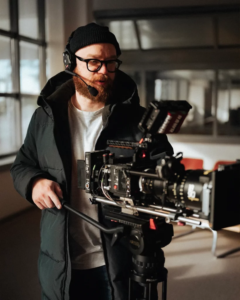 Chef opérateur derrière une caméra cinéma lors d’un tournage en décor intérieur.