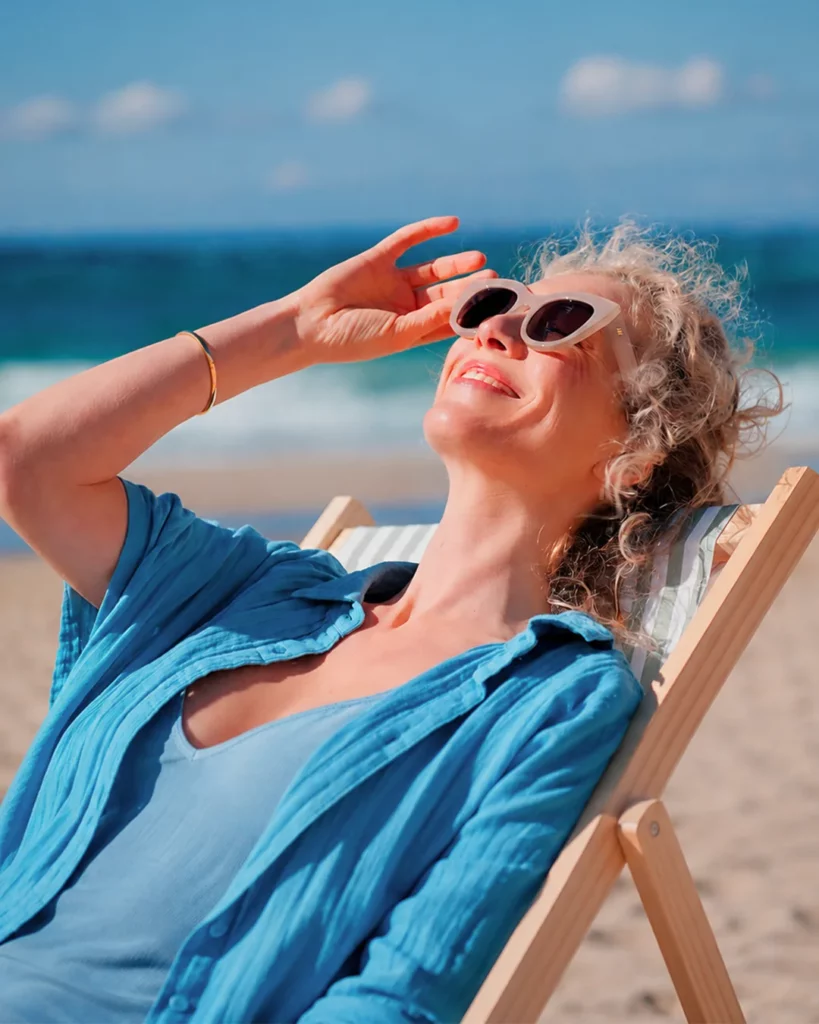 Femme portant des lunettes de soleil sur une plage dans une image vidéo travaillée pour créer une sensation estivale.